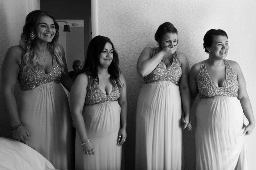 4 bridesmaids react to seeing the bride on her wedding day in black and white