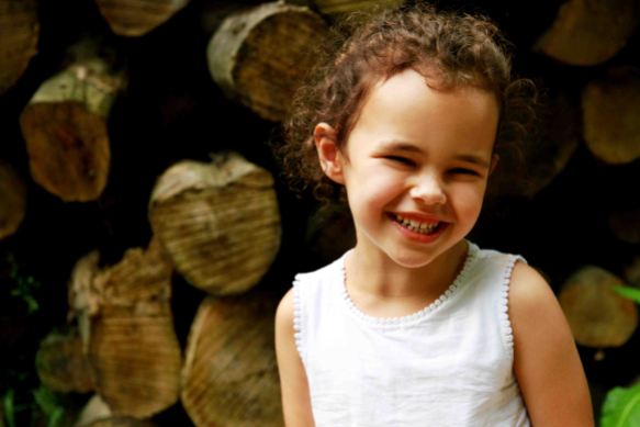 Child portrait in front of a stack of logs