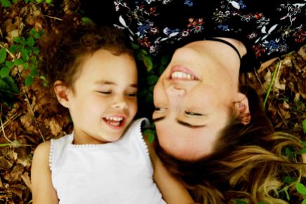 Mother and daughter laughing whilst lying on the grass