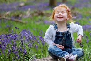 Laughing child portrait in a field of bluebells