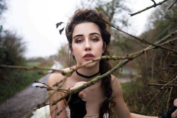Brunette model portrait with updo behind a branch